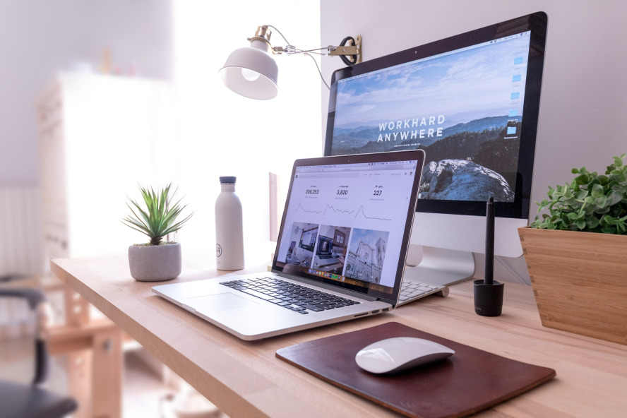 A desktop with a laptop and a monitor behind it.